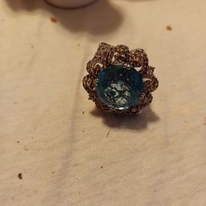 Ring. With blue stone in the middle. And diamonds around it.